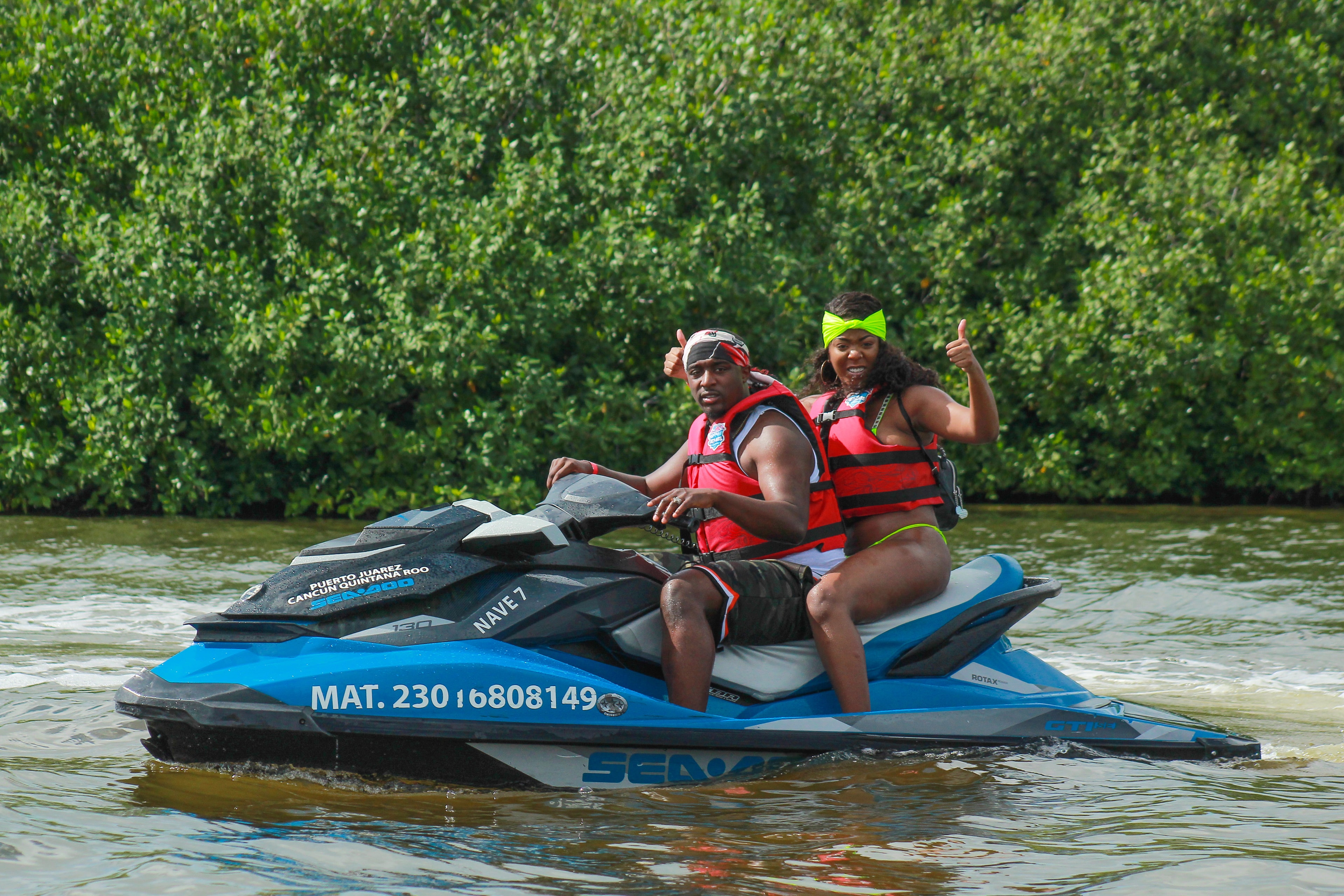 Happy couple on a Sea-Doo jet ski giving thumbs up in the Cancun mangrove lagoon
