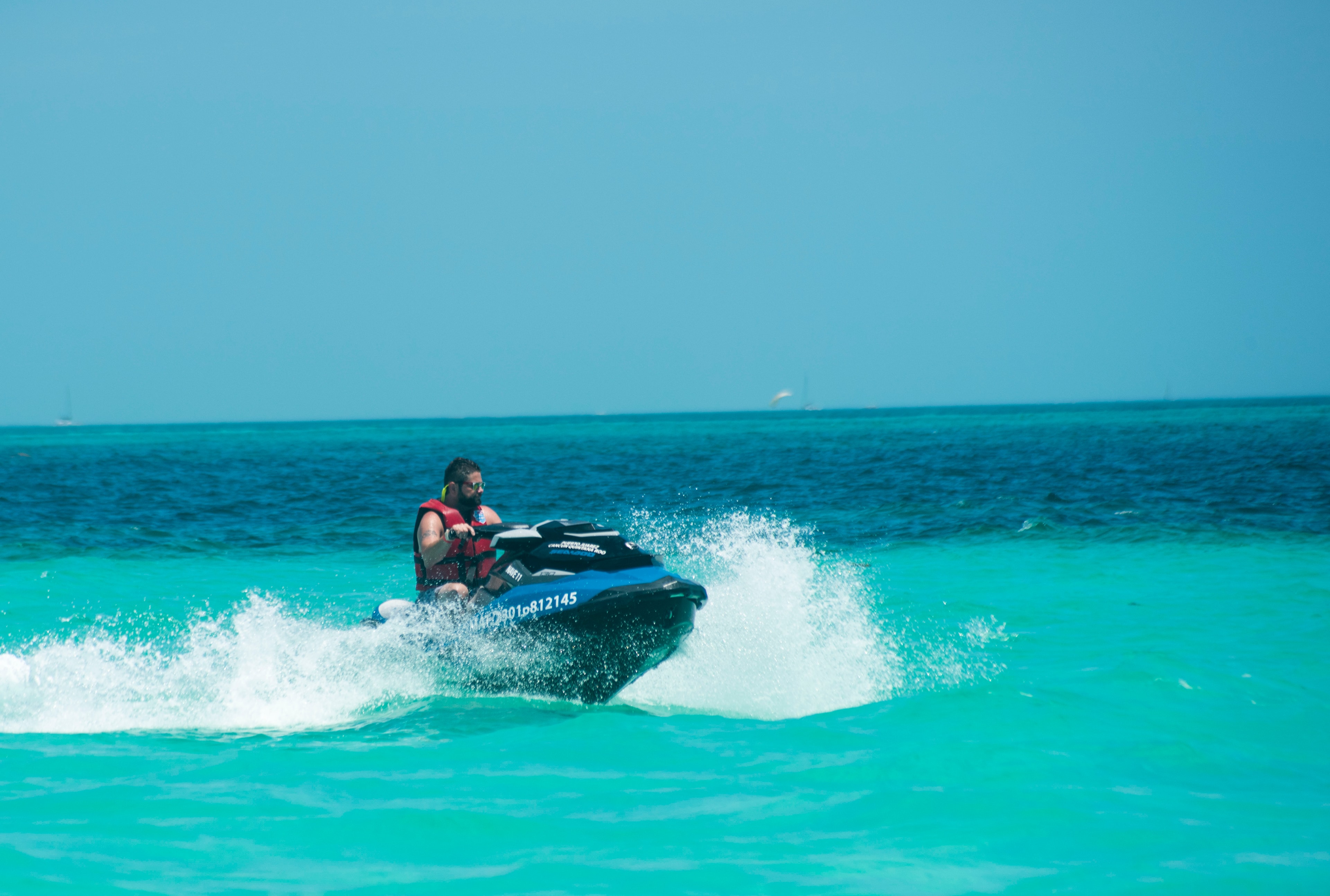 Solo rider on a jet ski cutting through turquoise Caribbean water at full speed