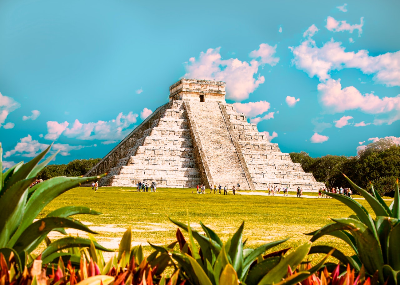 El Castillo pyramid at Chichen Itza framed by agave plants under a vivid blue sky